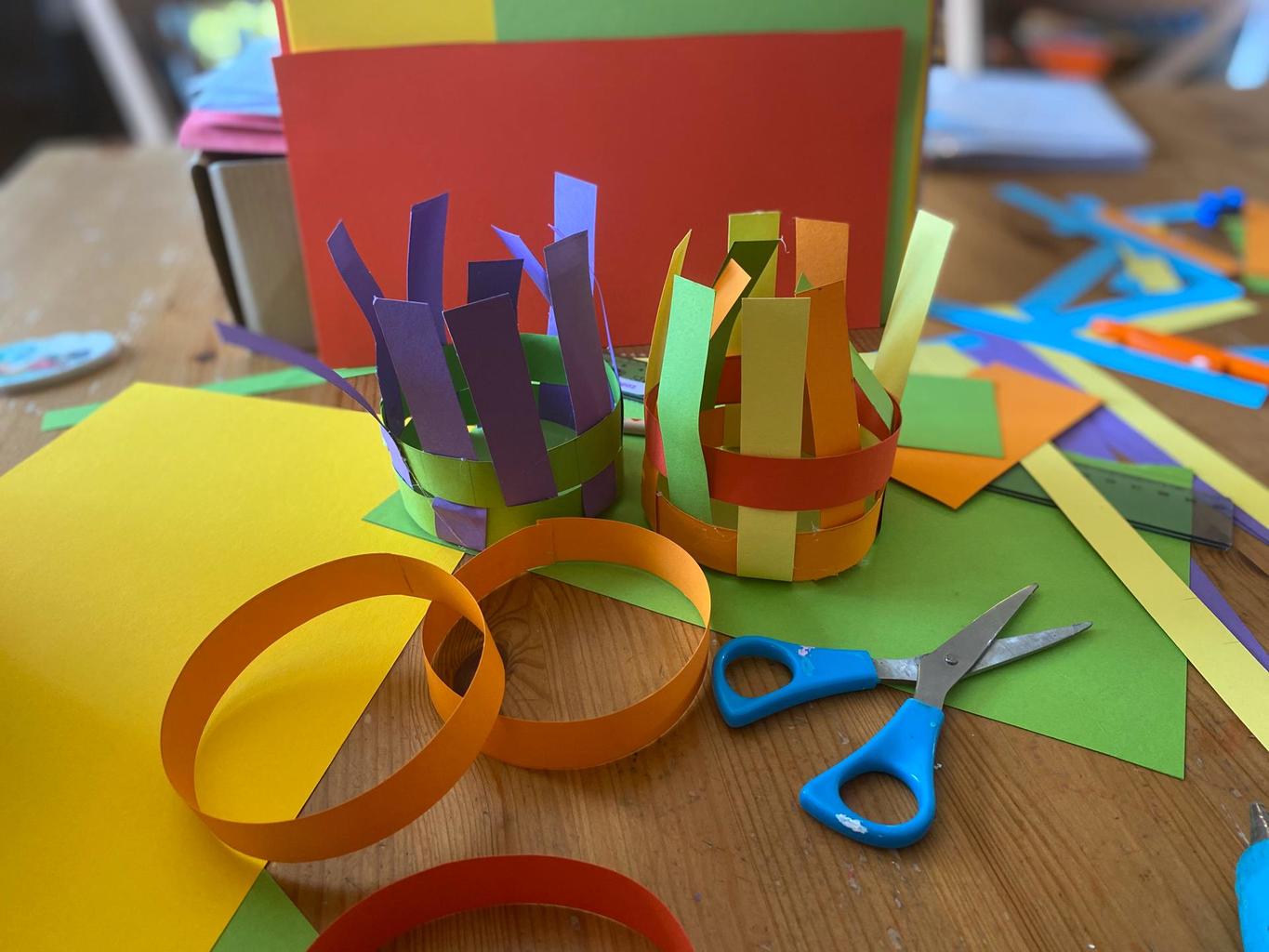 demostración de cómo hacer una cestita de tiras de cartón de varios colores
