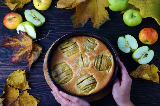 Tarta de manzana, completa la foto la decoración de manzanas frescas y hojas otoñales alrededor de molde con la tarta